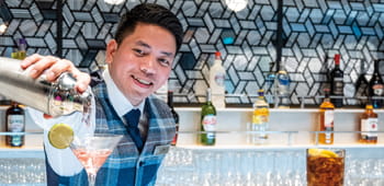 A bartender pouring a cocktail in The North Cape Bar on Spirit of Adventure